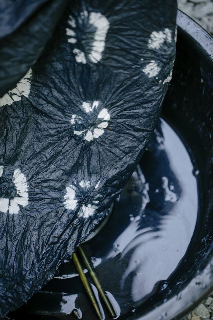 Close-up of artisanal tie-dye textile soaking in water for unique pattern creation.