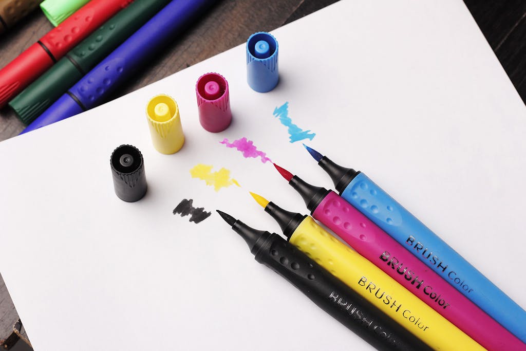 Top view of colorful brush markers with caps on white paper, perfect for art projects.