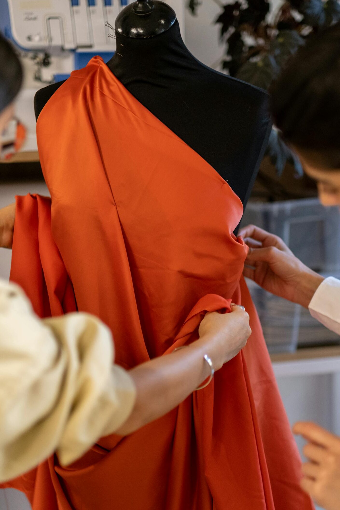 Two designers collaborate in a fashion studio, adjusting fabric on a mannequin.