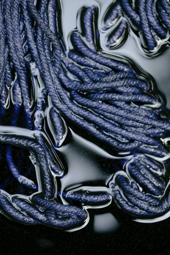 Detailed view of blue yarns soaking in liquid dye, showcasing textile crafting techniques.